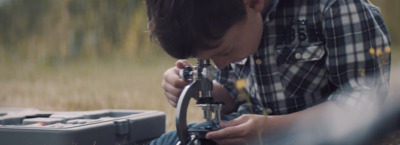 a young boy is looking through a microscope