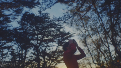 a man in a red shirt standing in front of trees