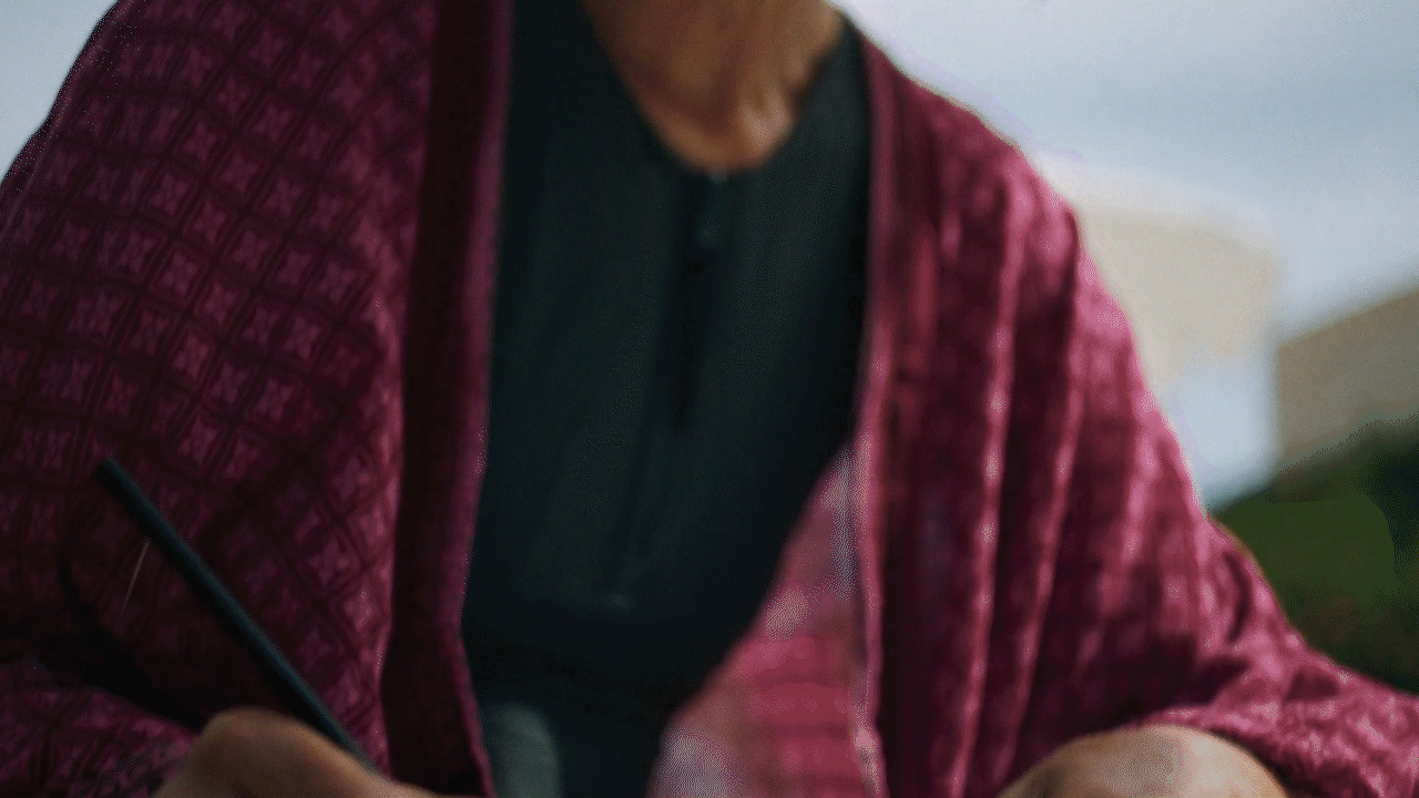 a woman in a kimono writing on a piece of paper