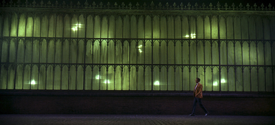 a man walking down a sidewalk next to a tall building