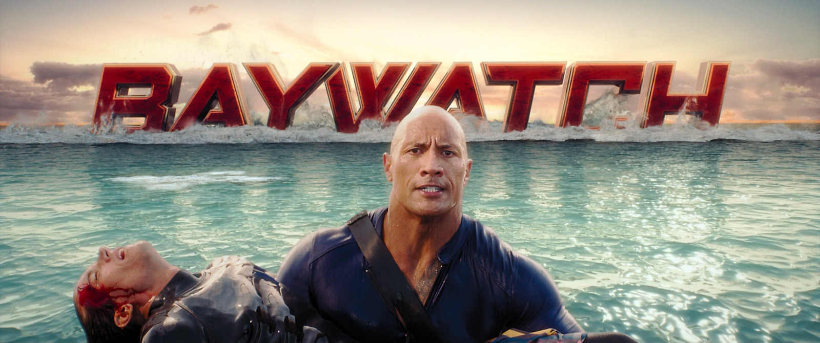 a man sitting in the water in front of the baywatch sign