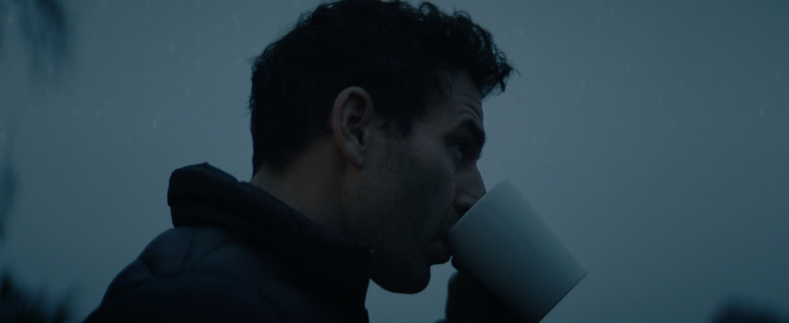 a man drinking a cup of coffee in the rain