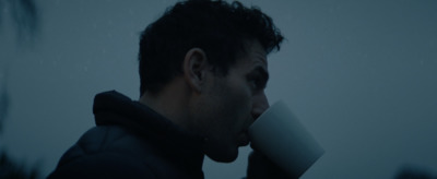 a man drinking a cup of coffee in the rain