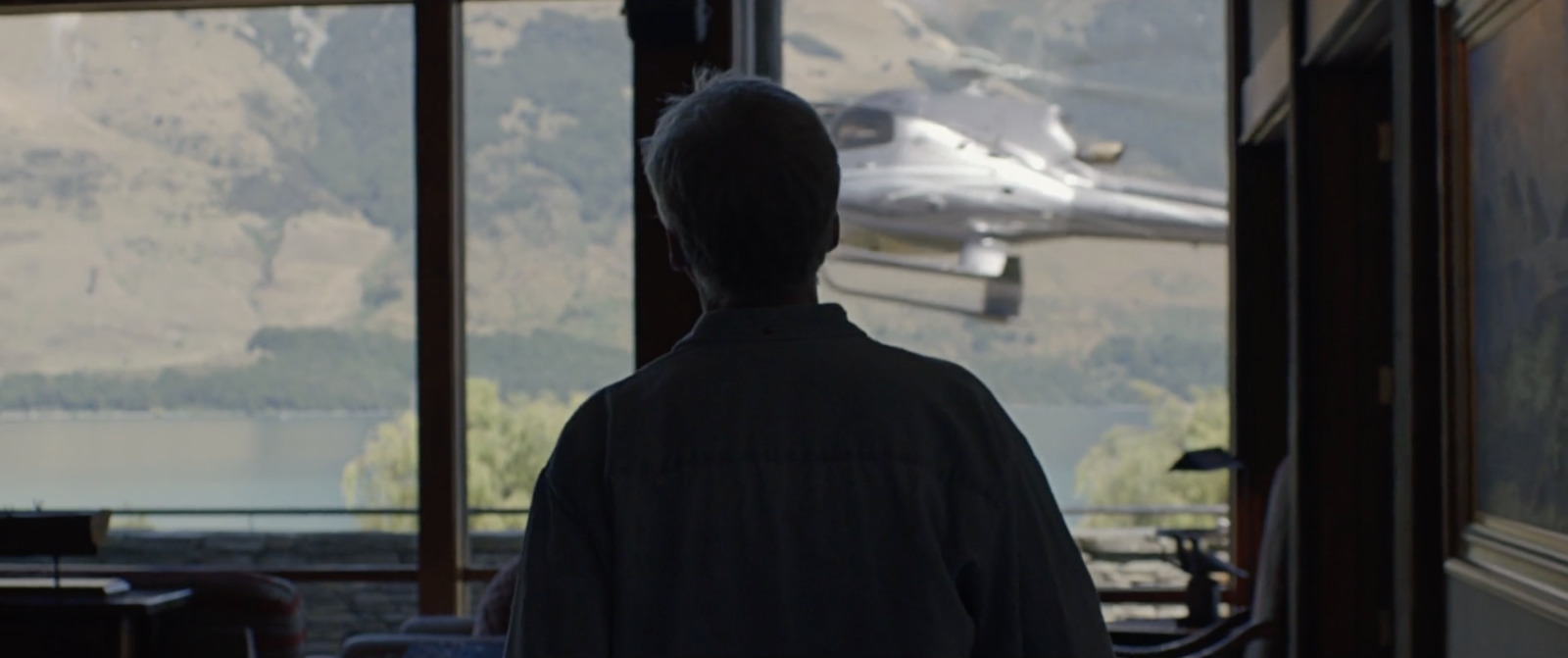 a man standing in front of a window looking at a plane