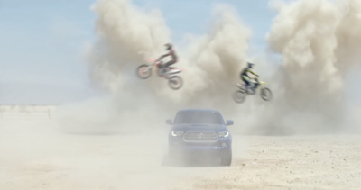 a car driving down a dirt road next to a motorcycle