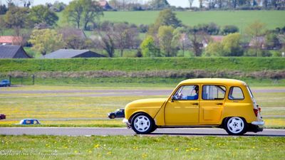 a small yellow car driving down a road