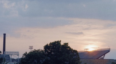 the sun is setting over a baseball field