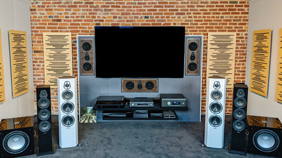 a room with speakers, a television and a brick wall