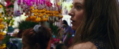 a woman standing in front of a bunch of flowers