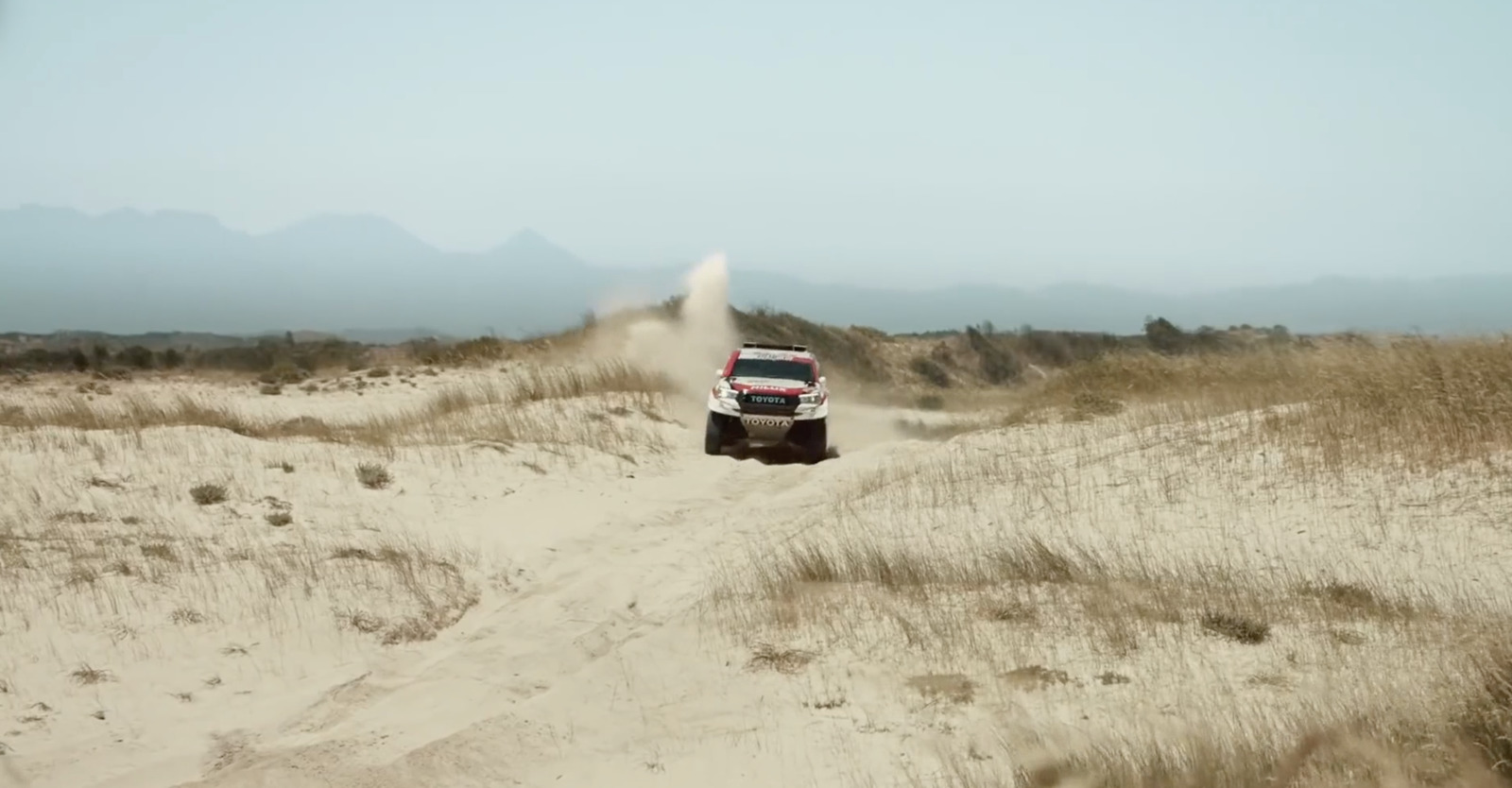 a truck driving down a dirt road in the desert