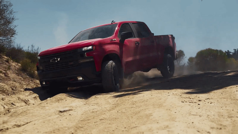 a red truck driving down a dirt road