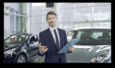 a man in a suit holding a clipboard in front of a car