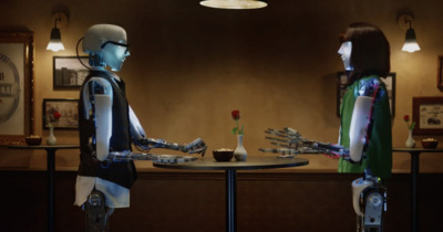 a robot and a woman sitting at a table