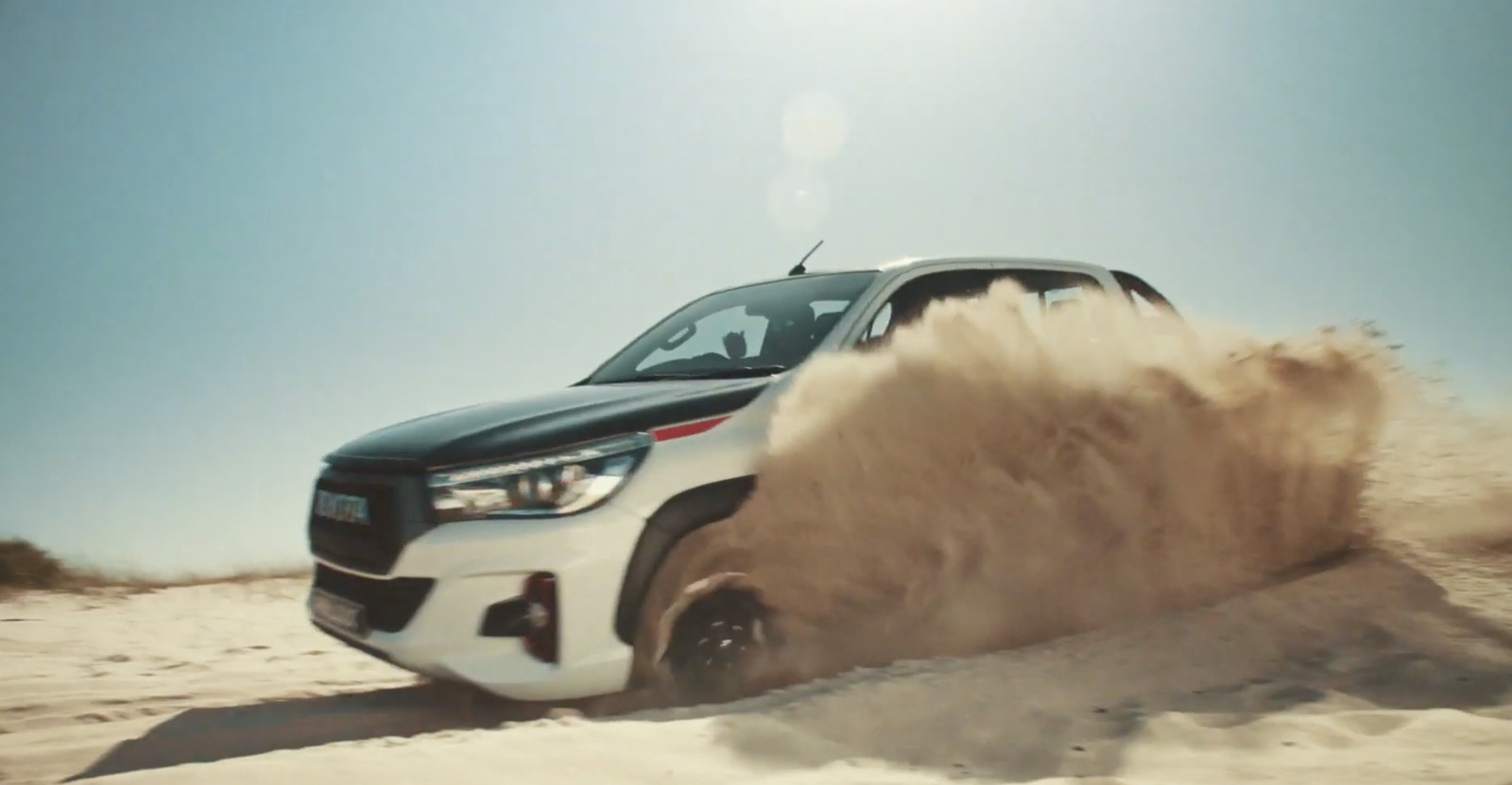 a black and white truck driving through sand