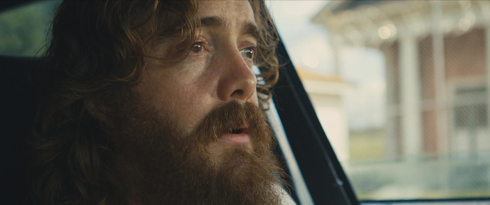 a man with long hair and a beard sitting in a car