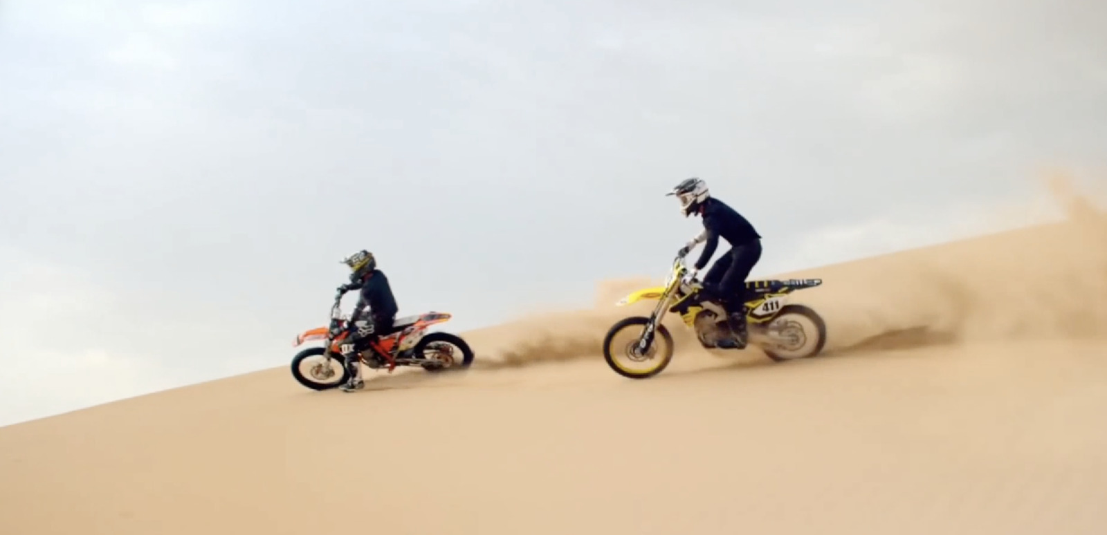 two people riding dirt bikes in the desert