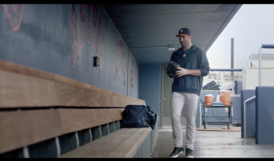 a man standing next to a baseball bat in a dugout