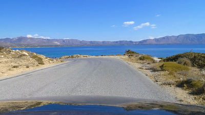 a car driving down a road next to a body of water