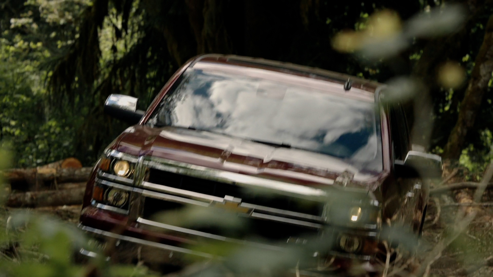 a red truck driving through a forest filled with trees