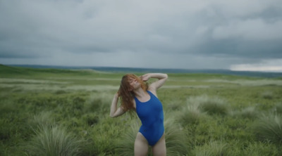 a woman in a blue bodysuit standing in a field