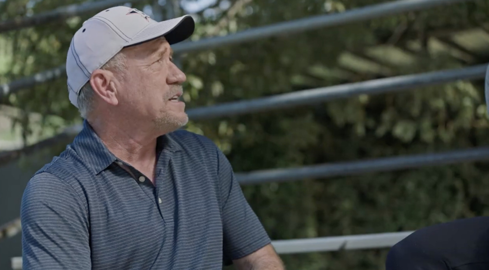 an older man wearing a baseball cap sitting next to a younger man