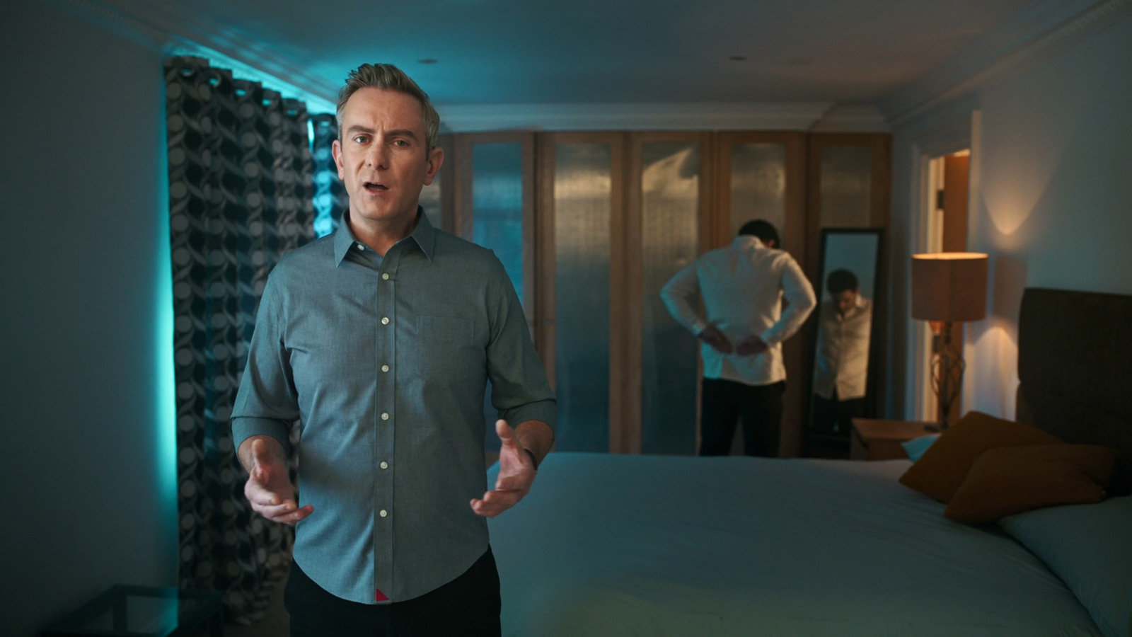 a man standing in front of a bed in a bedroom