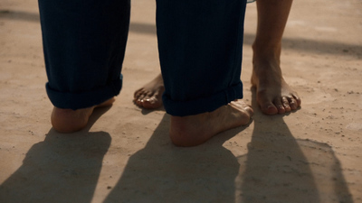 a person standing with their bare feet in the sand