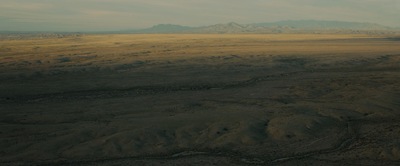 an aerial view of a plain with mountains in the distance