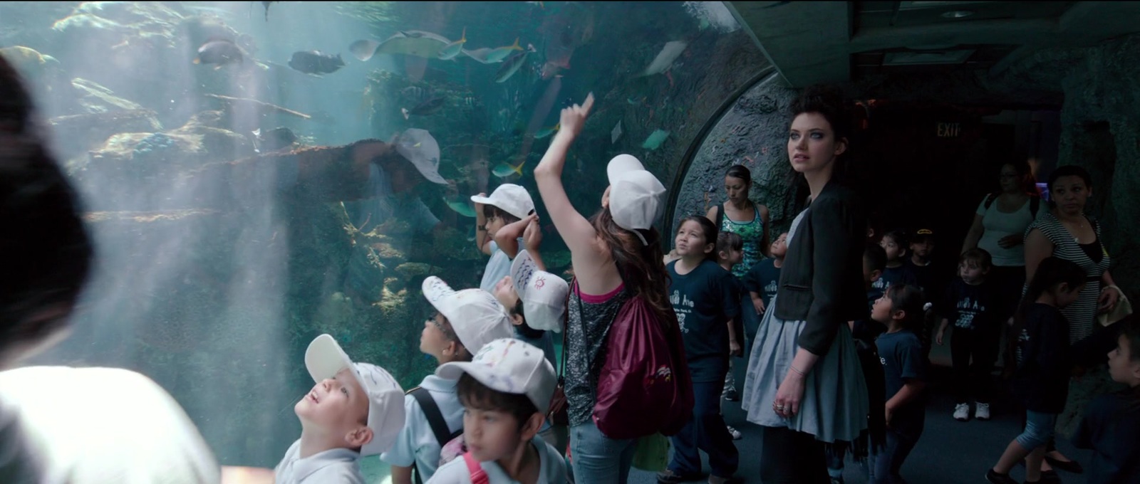 a group of children standing in front of a large aquarium