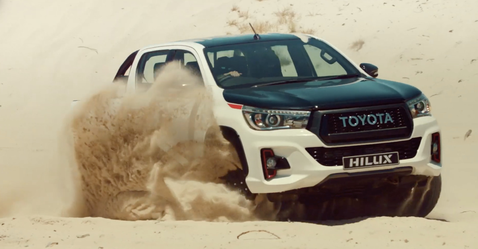 a white truck driving through a sandy area