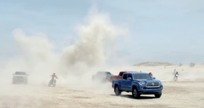 a blue truck driving down a dirt road