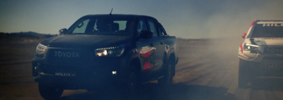 a couple of cars driving down a dirt road