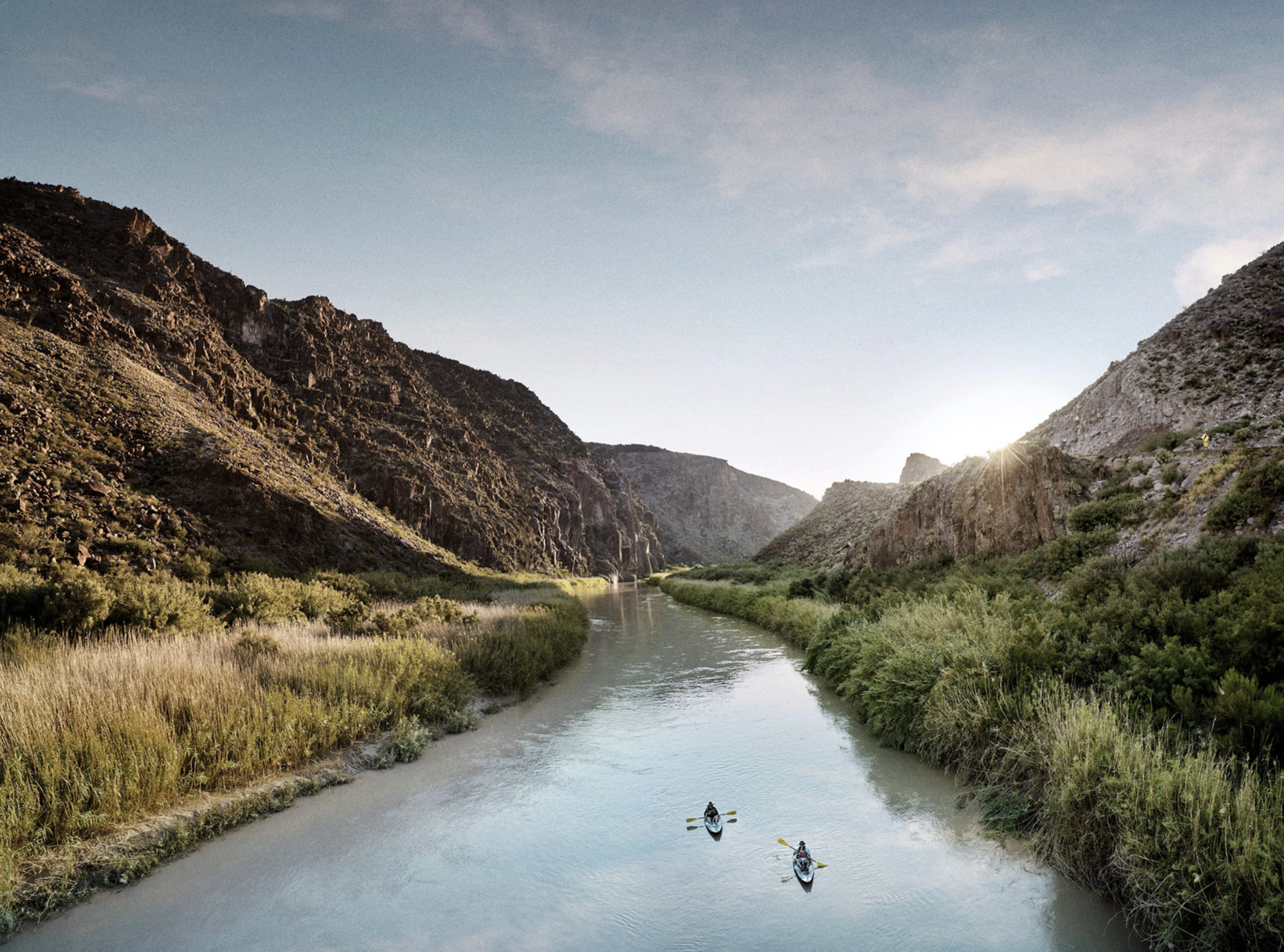 two people are kayaking down a river in the mountains