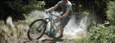 a man riding a bike through a puddle of water