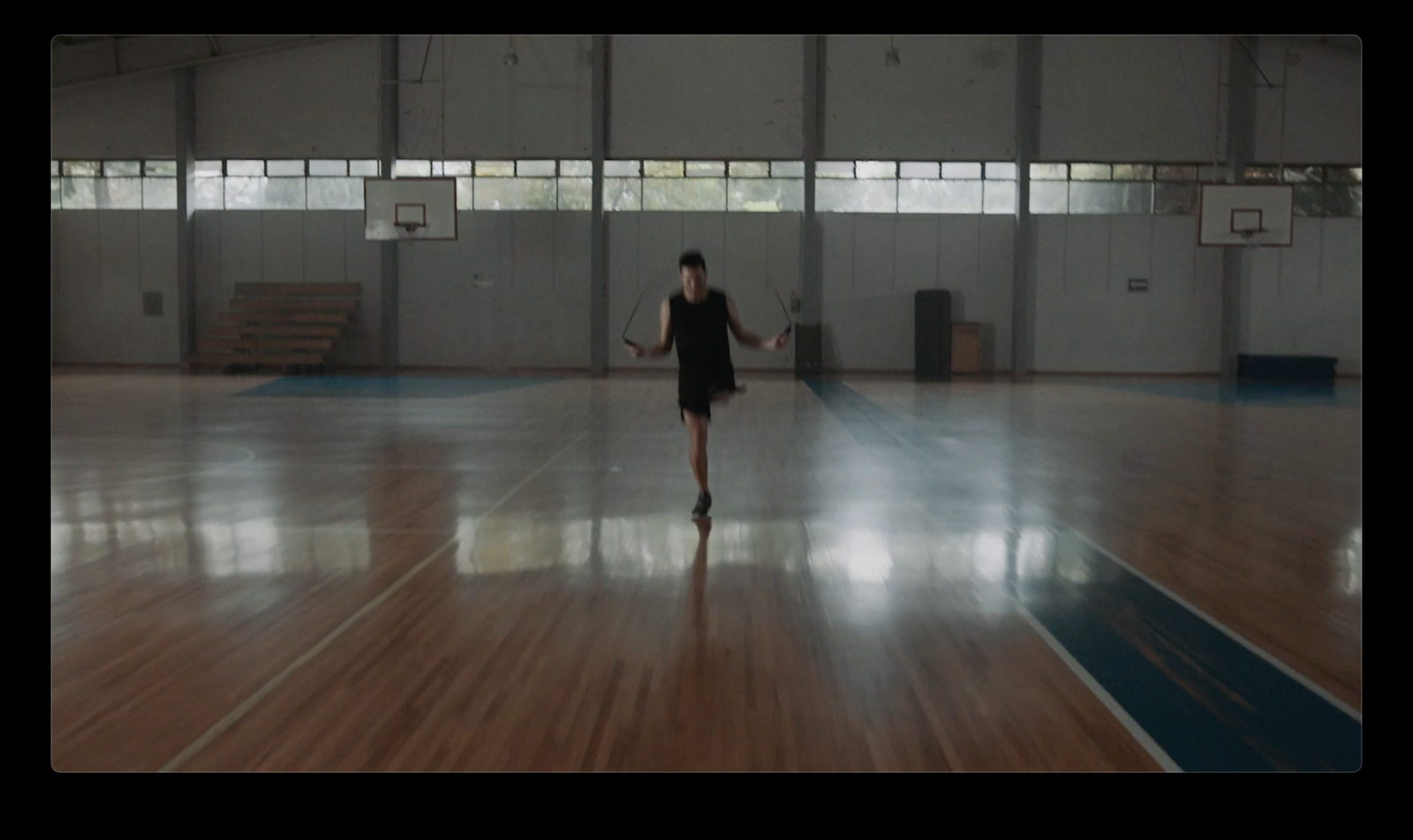 a woman standing in a gym holding a tennis racquet