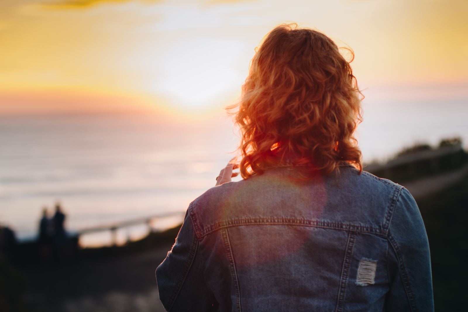 a woman looking out at the ocean at sunset