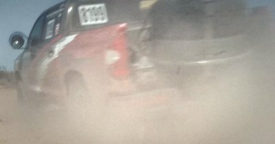 a red pick up truck driving down a dirt road