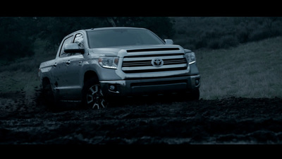 a silver truck driving down a dirt road