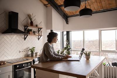 a woman sitting at a kitchen counter using a laptop