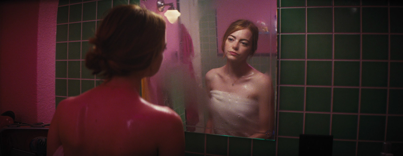 a woman standing in front of a bathroom mirror