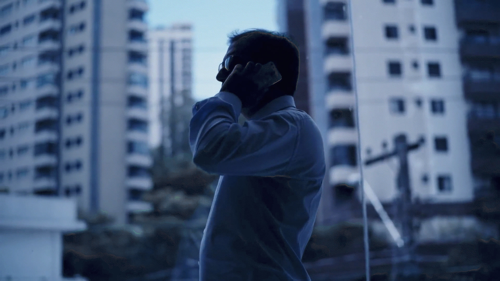 a man talking on a cell phone in front of tall buildings