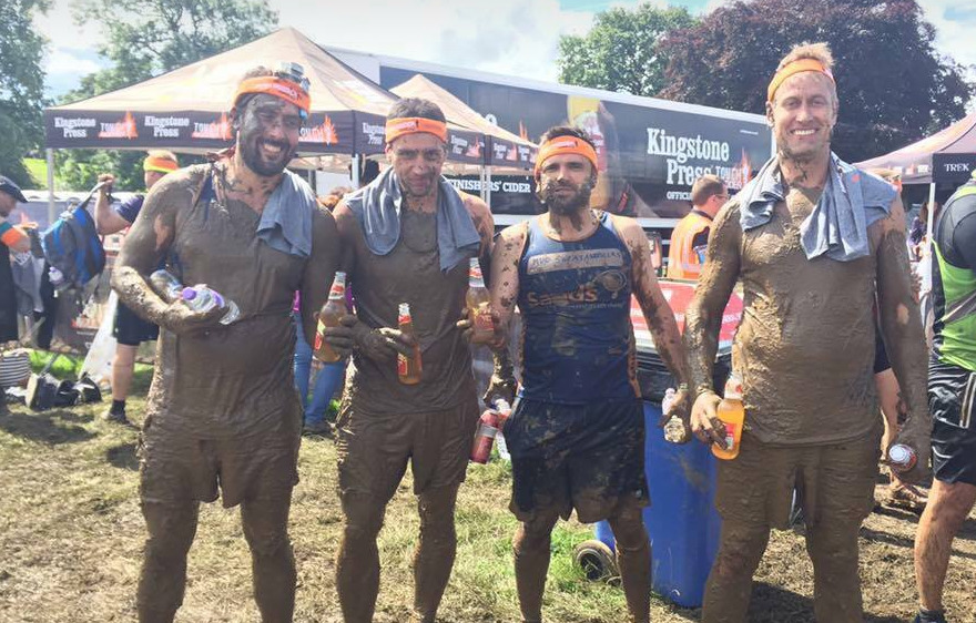 a group of men standing next to each other covered in mud