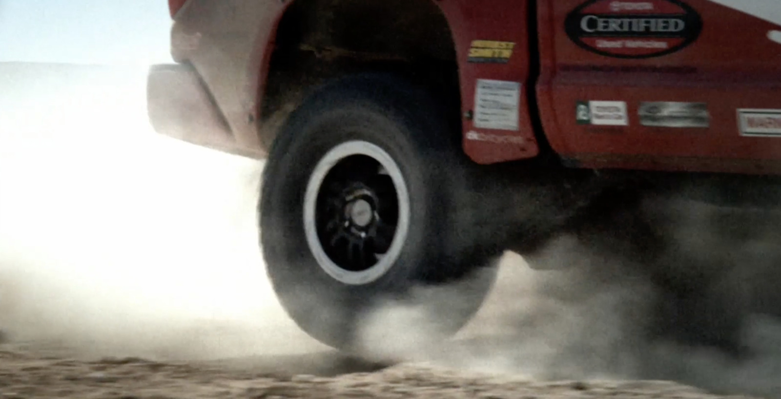 a red truck driving down a dirt road