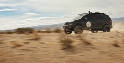 a black suv driving through the desert on a cloudy day