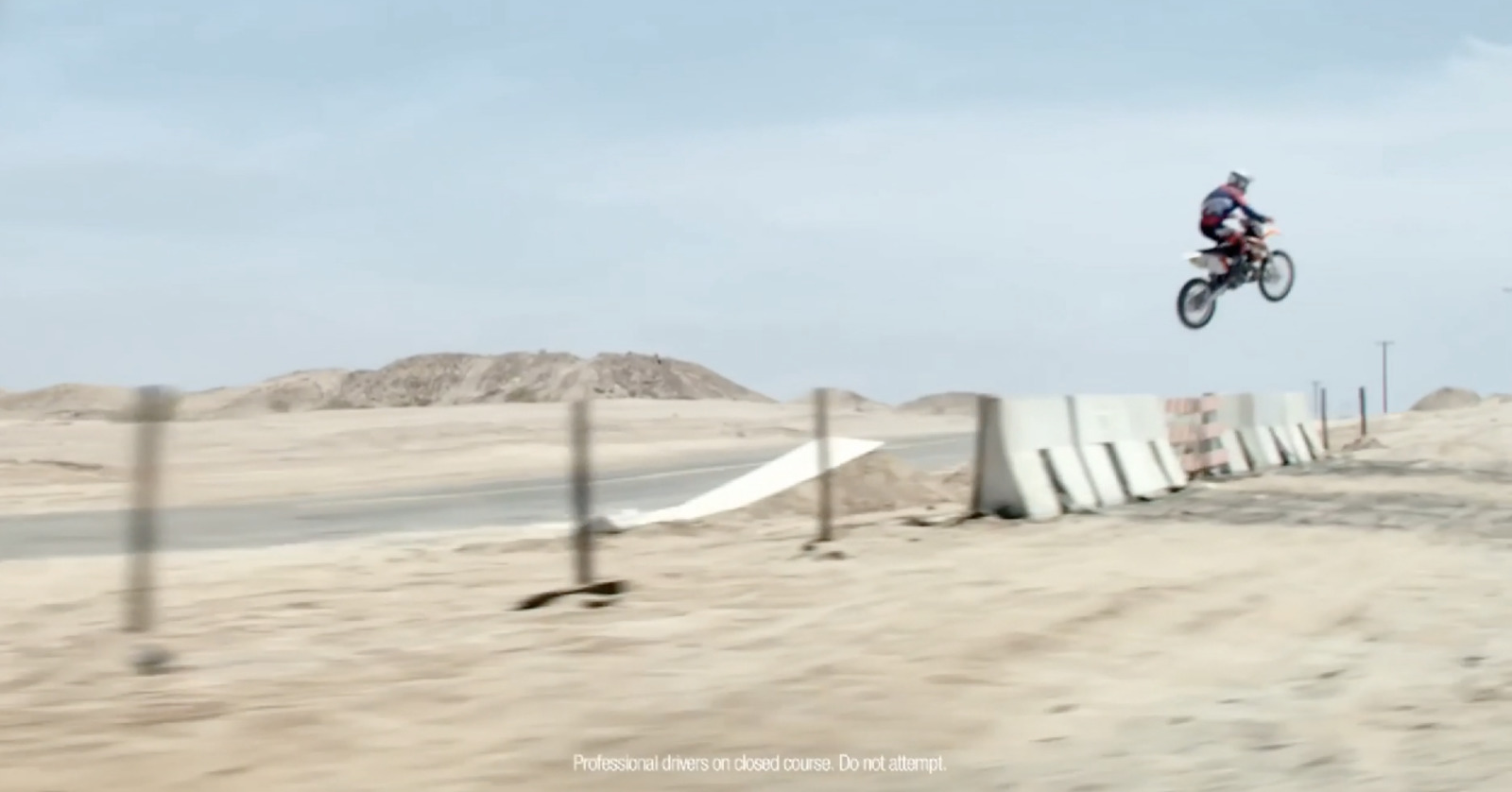 a person on a dirt bike jumping over a fence