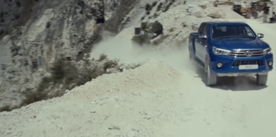 a blue truck driving down a snow covered road