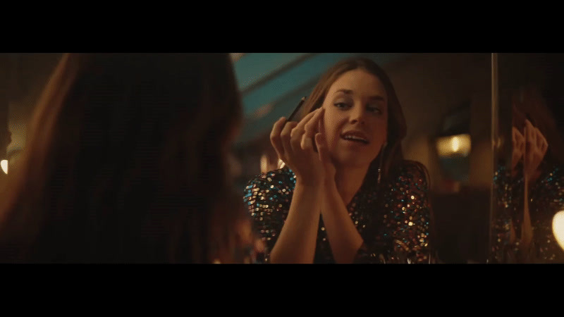 a woman talking to another woman in front of a mirror