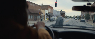 a man driving a car down a street next to a traffic light