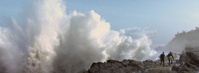 a couple of people standing on top of a rocky cliff