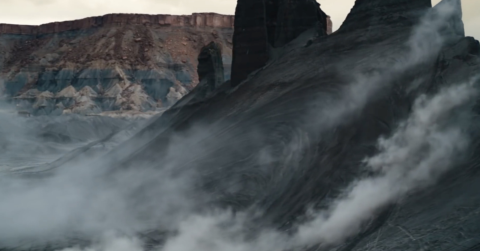 a mountain covered in fog with a mountain in the background